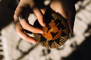 Woman reaches for a low-dose recreational edible. The edible is a fruit jelly that tastes like blood orange.