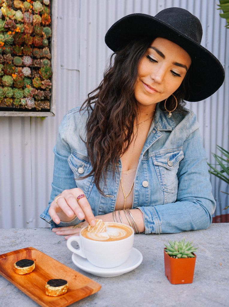 Woman enjoys a recreational edible after a long day. She dips a 3Leaf Coconut Oatmeal Cookie into a latte.