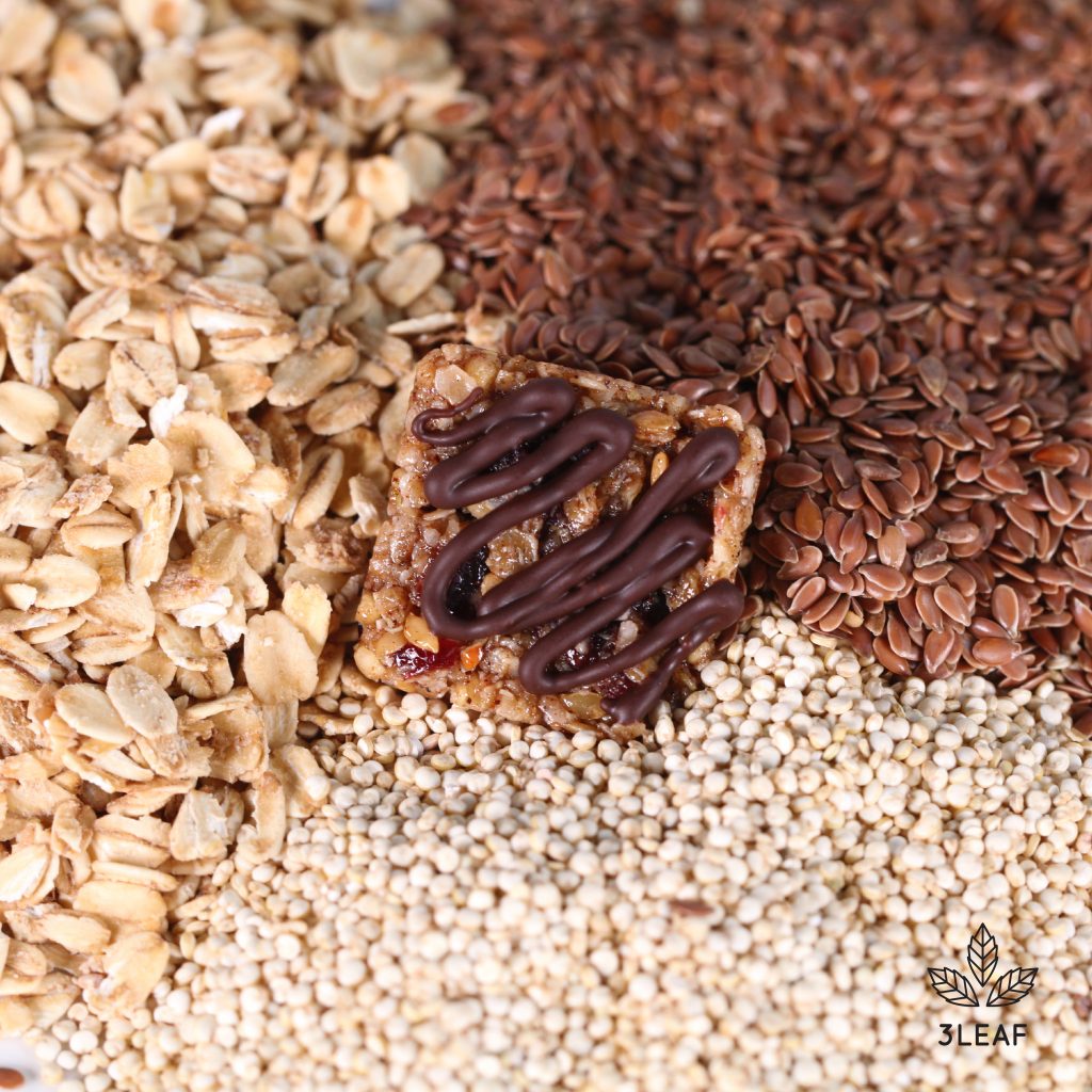 3Leaf's Quinoa Granola Bite surrounded by granola, flax, and quinoa.