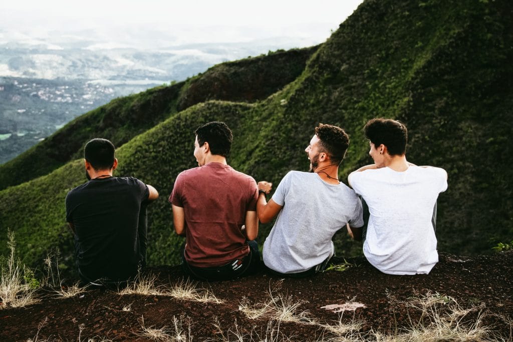 Four men sitting at the edge of a mountain, laughing